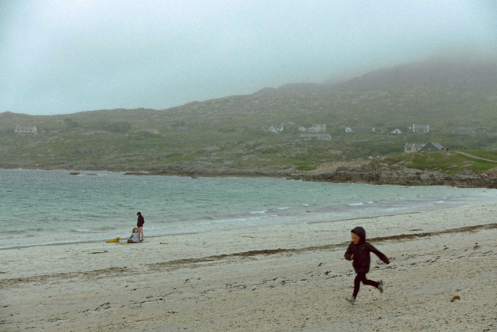 a little girl running on the beach with a kite