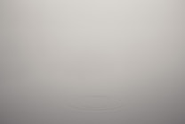 A minimalistic scene with a soft gray background and a subtle ripple effect in the center, creating a sense of calm and simplicity.