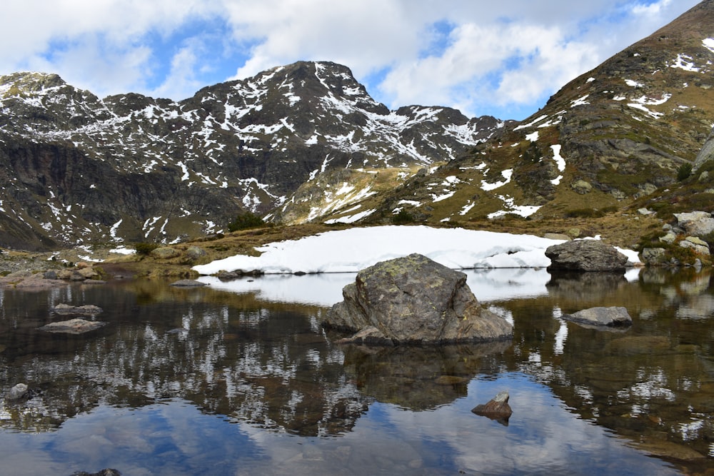 a mountain range with a lake surrounded by snow