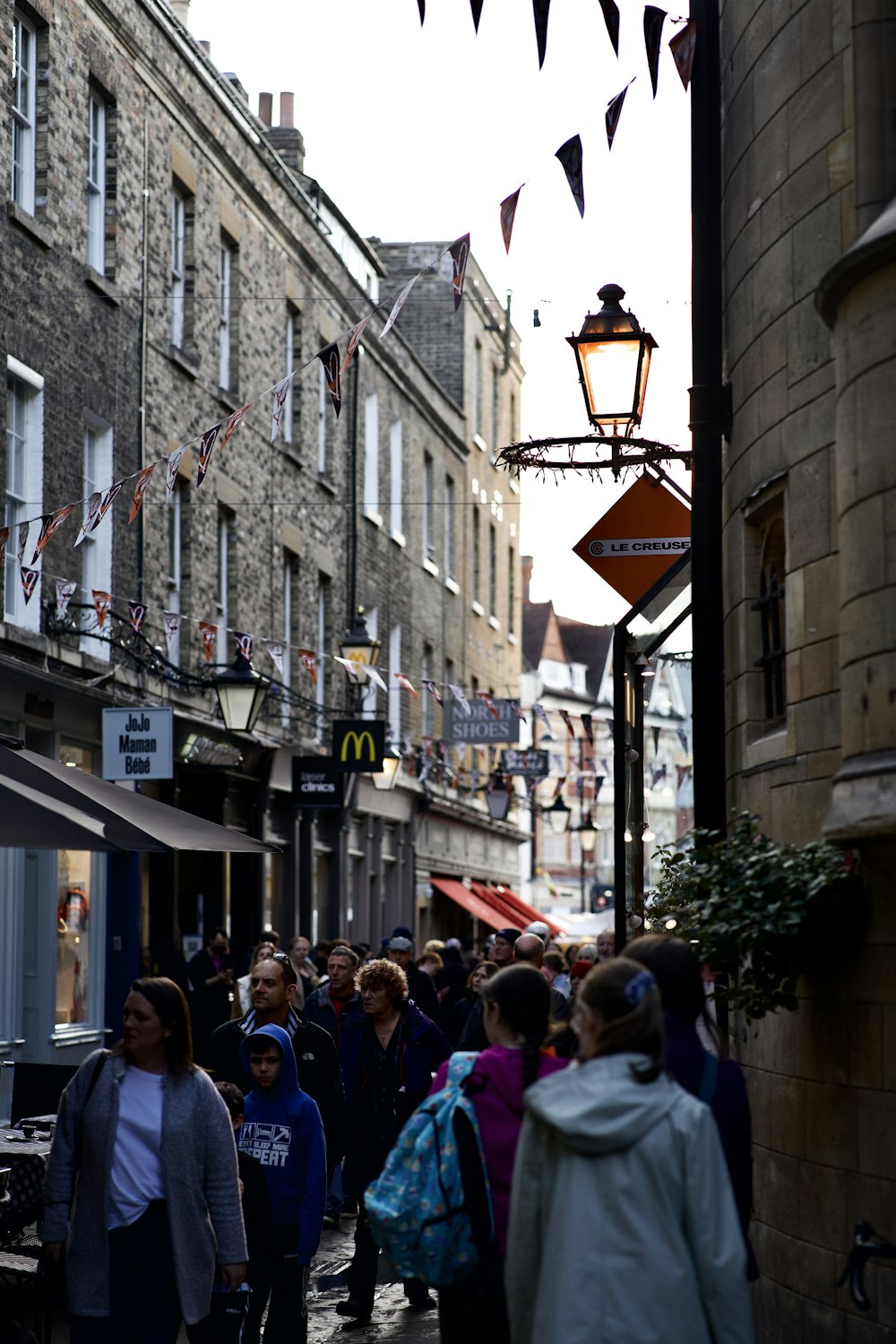 a crowd of people walking down a street next to tall buildings