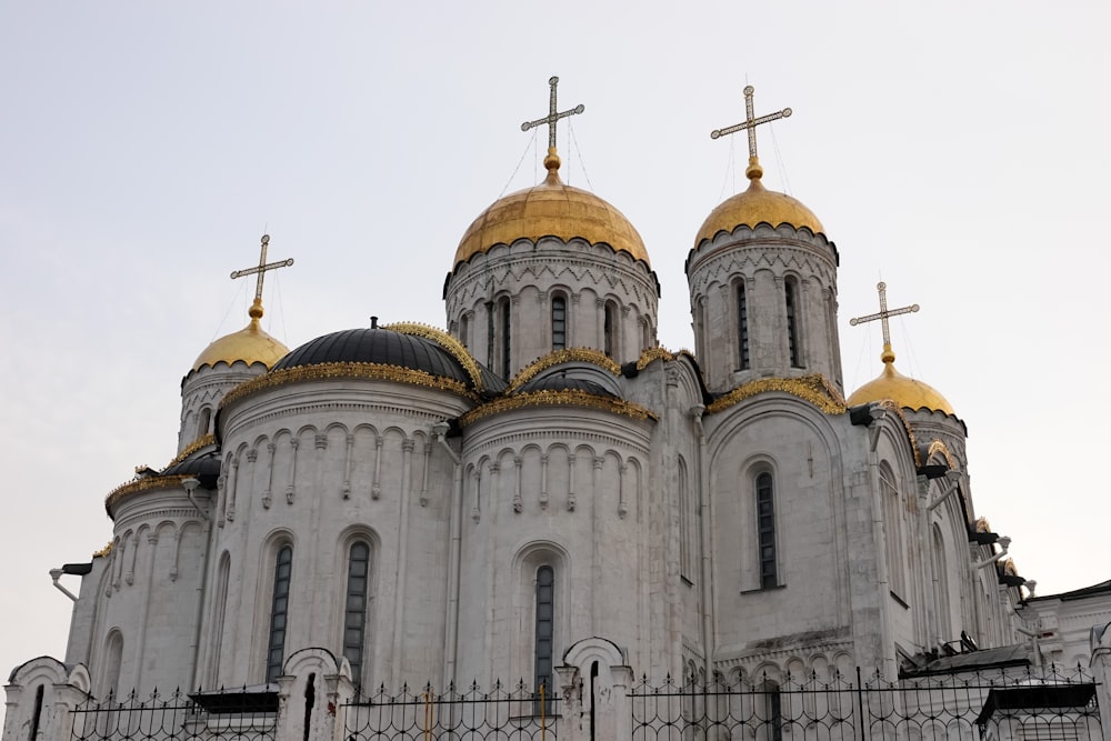 a large white building with gold domes and crosses on top