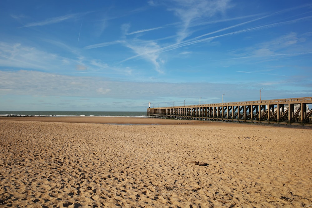 a long pier on a beach with footprints in the sand