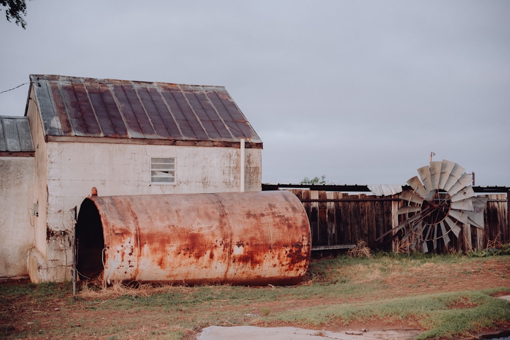 an old rusted water tank next to a barn