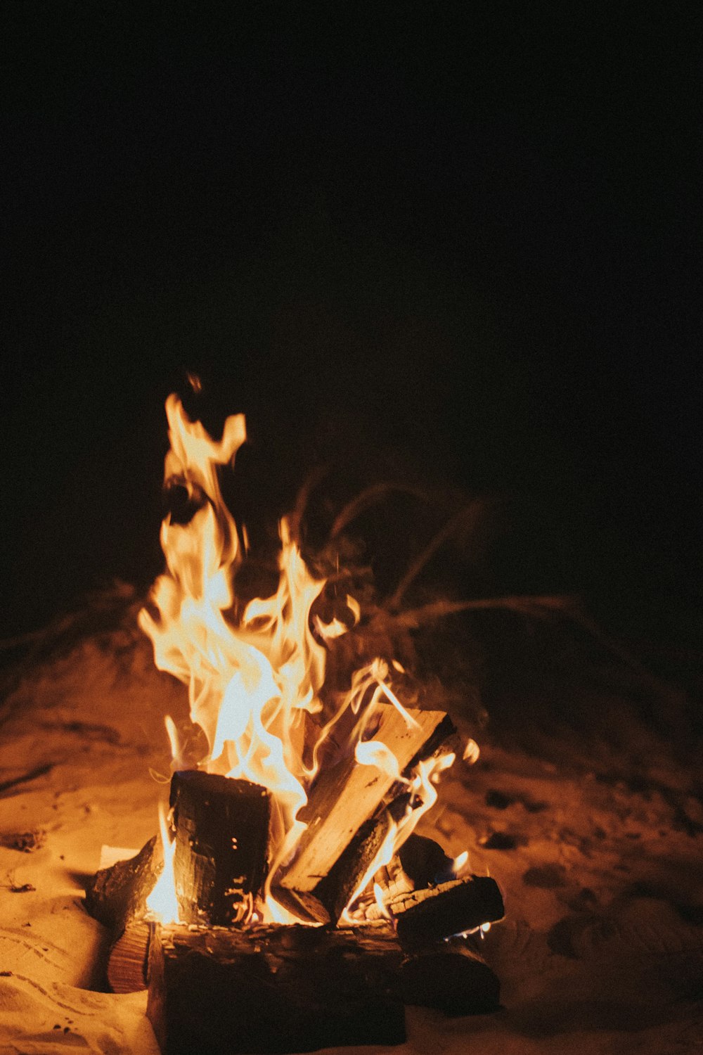 Un feu de camp brûlant dans le sable la nuit