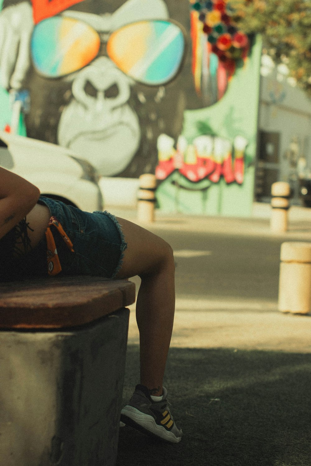 a woman sitting on a bench in front of a mural