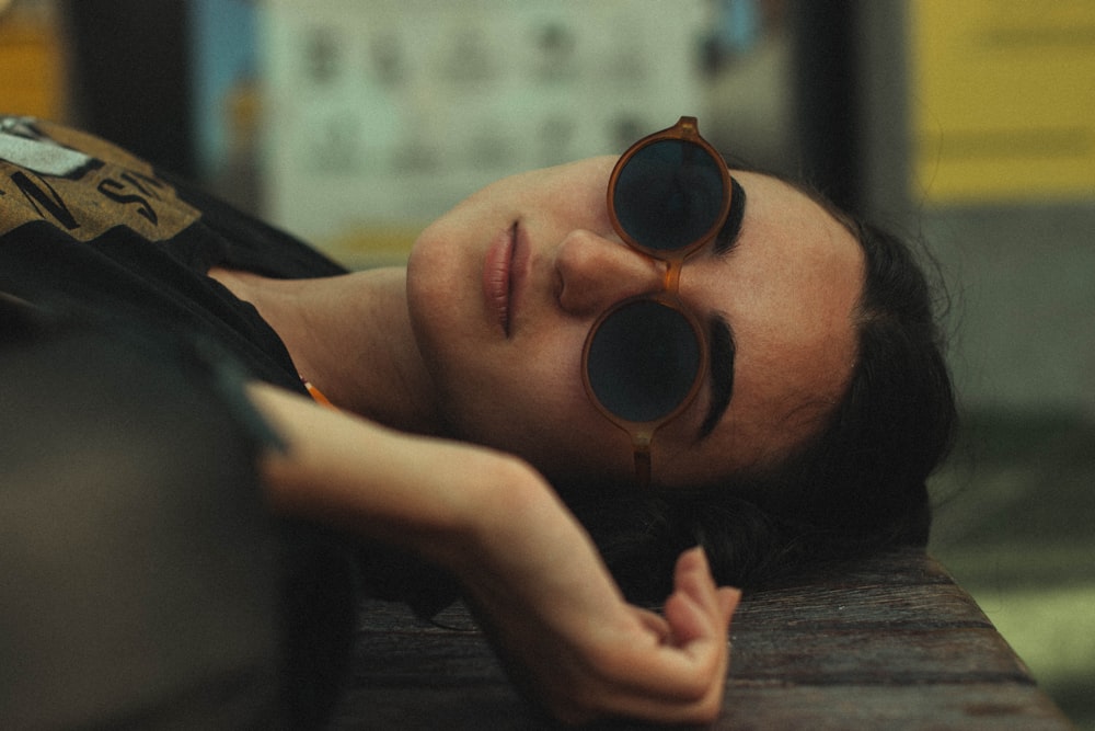 a woman laying on a bench with her eyes closed