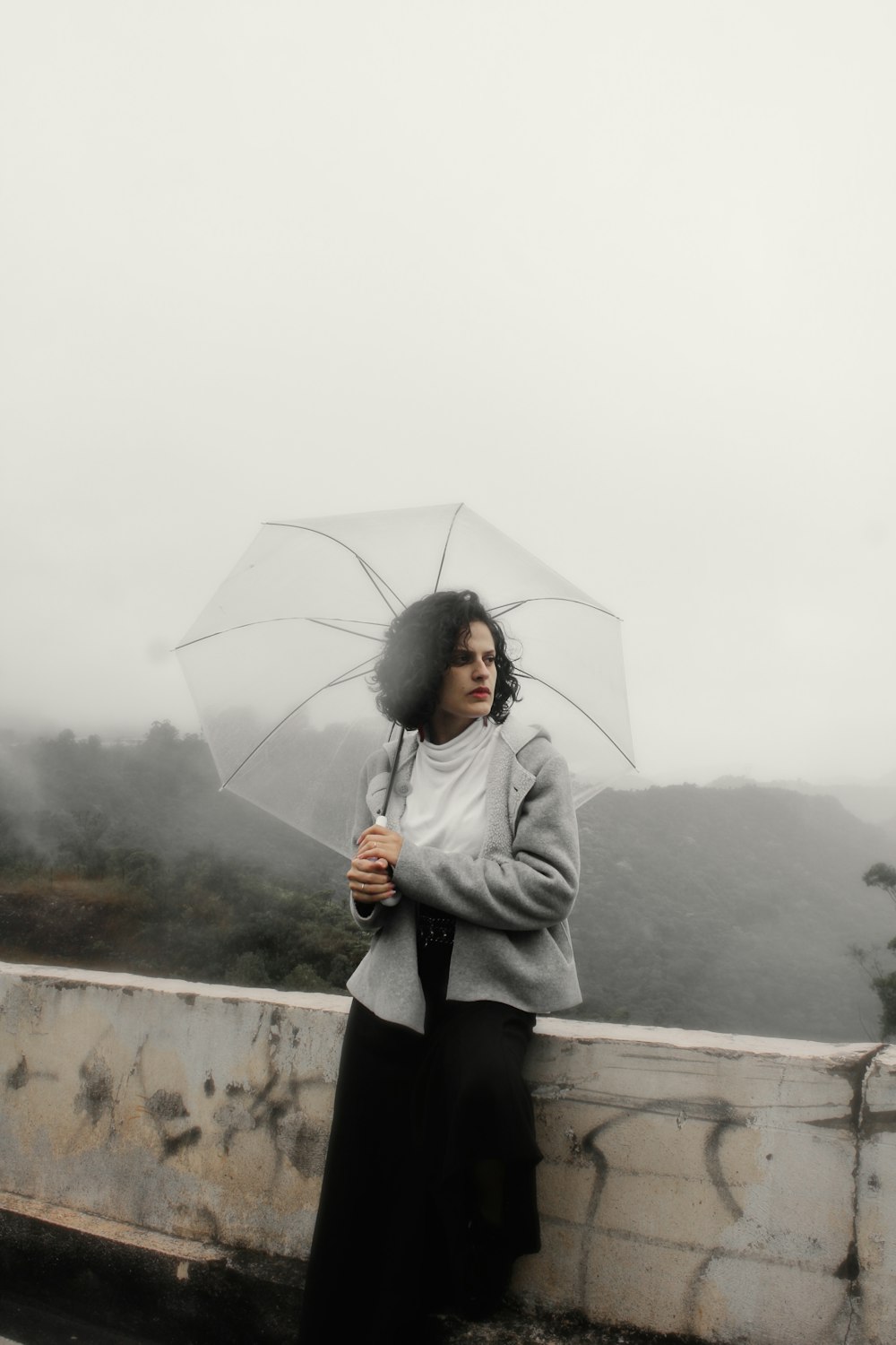 a woman standing on a bridge holding an umbrella