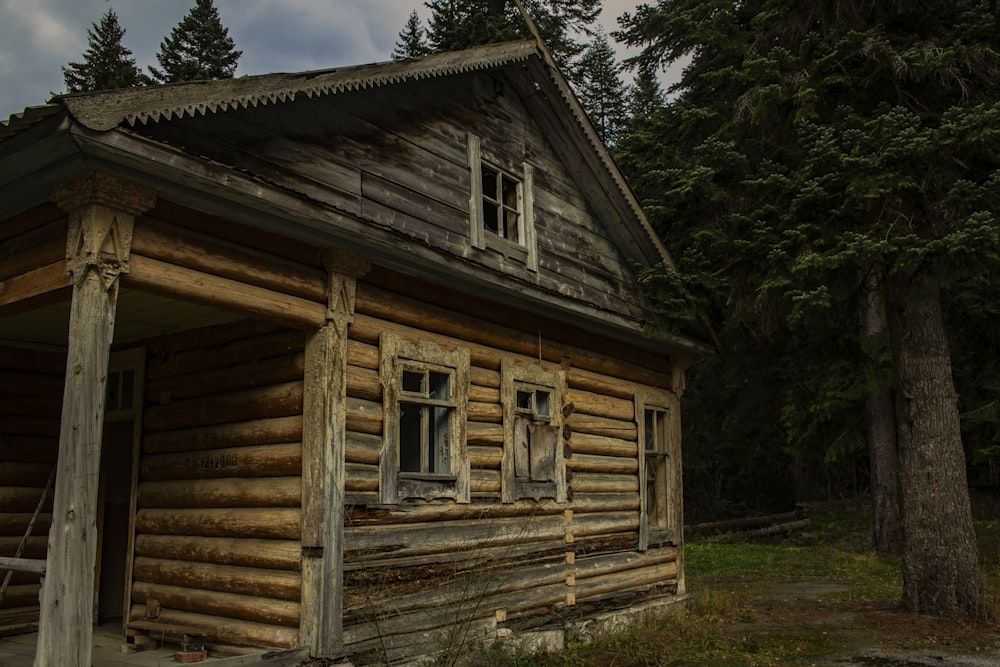an old log cabin in the woods with a porch
