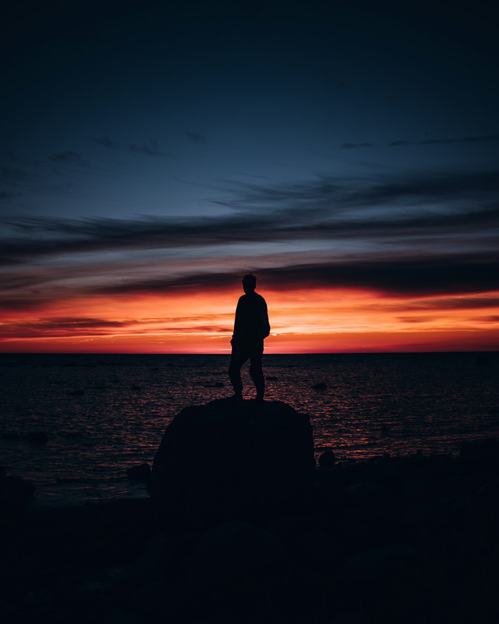 a man standing on top of a rock near the ocean