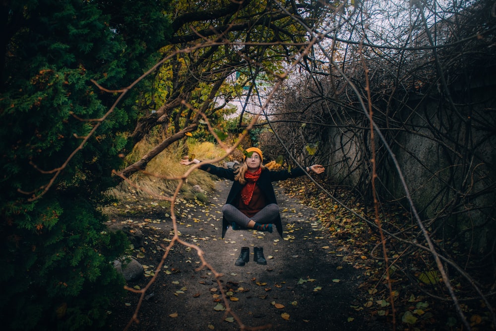 a woman sitting on a path surrounded by trees