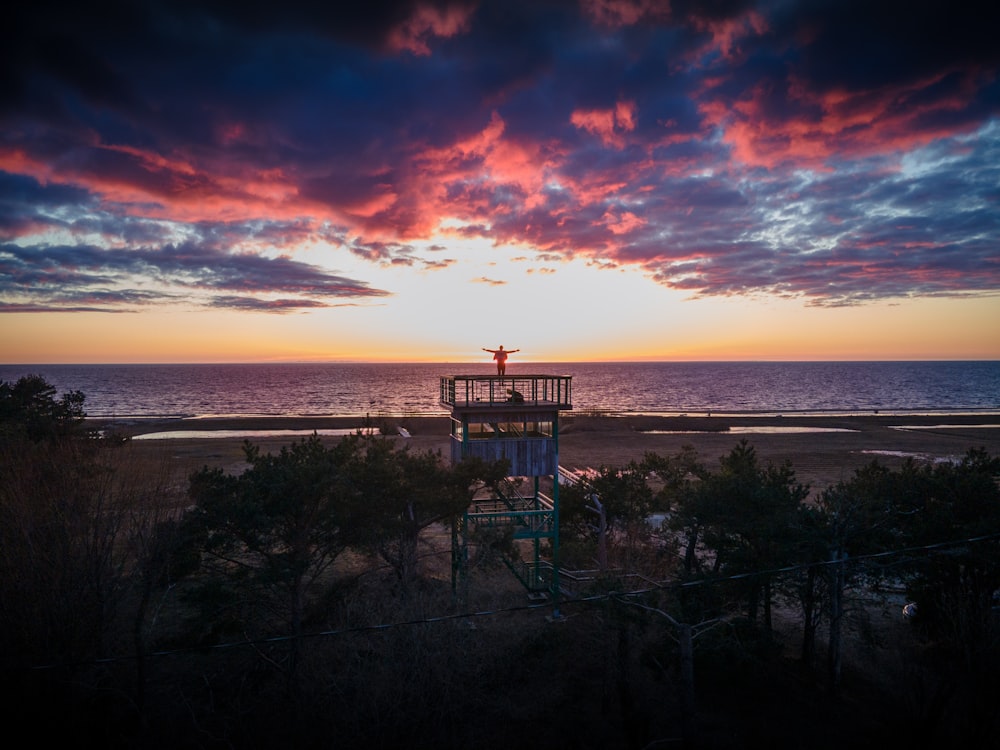 a sunset over a beach with a life guard tower