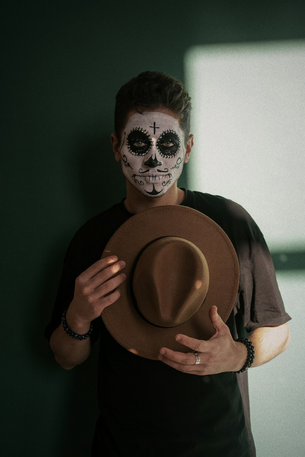 a man wearing a skeleton face paint holding a hat