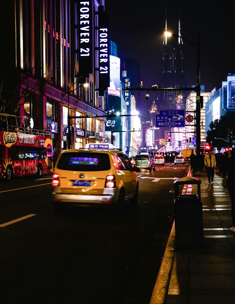 a taxi cab driving down a city street at night