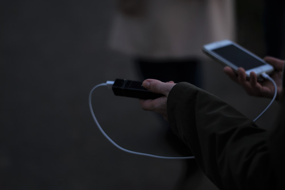 uma pessoa segurando um telefone celular e um carregador