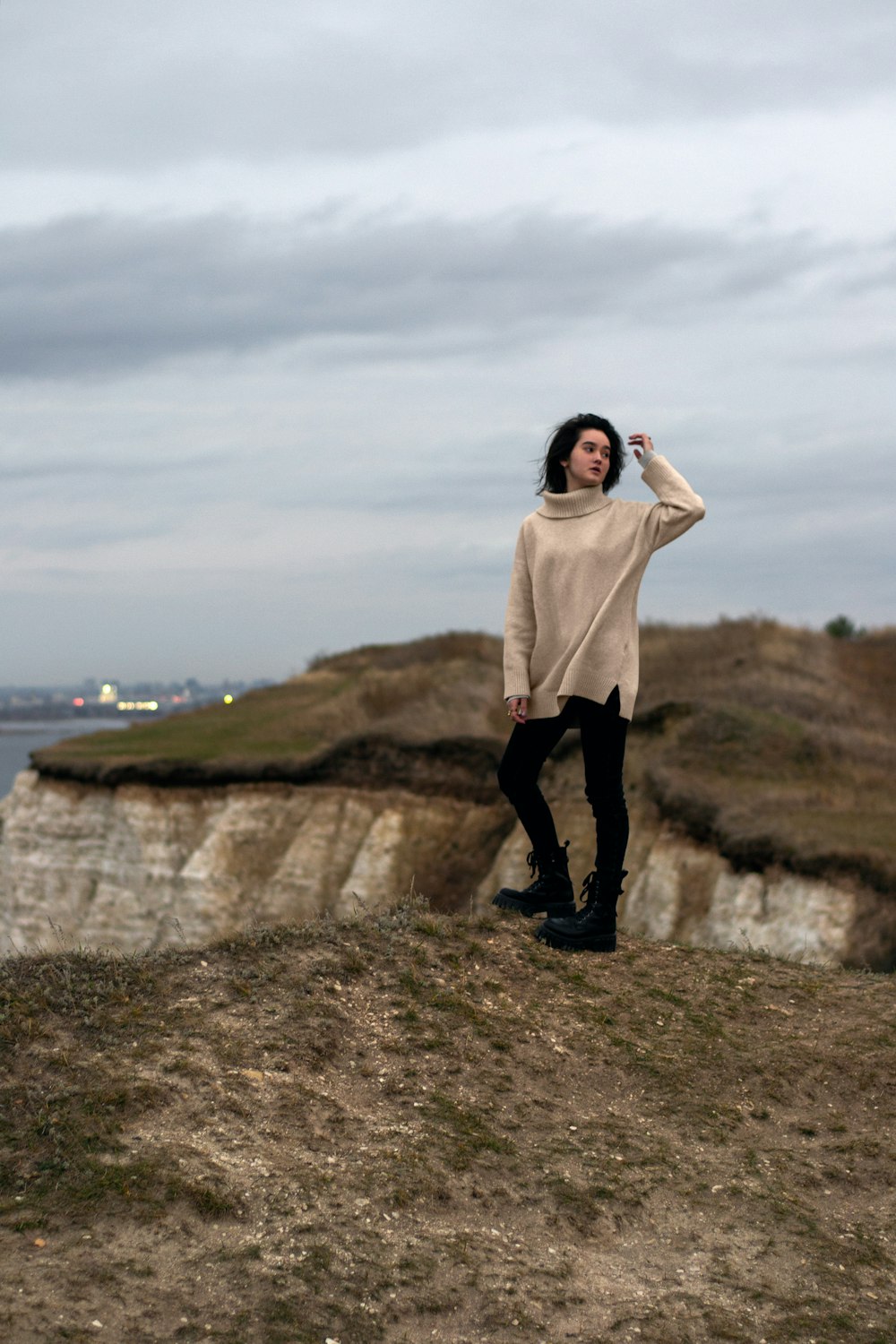 a woman standing on top of a hill next to the ocean