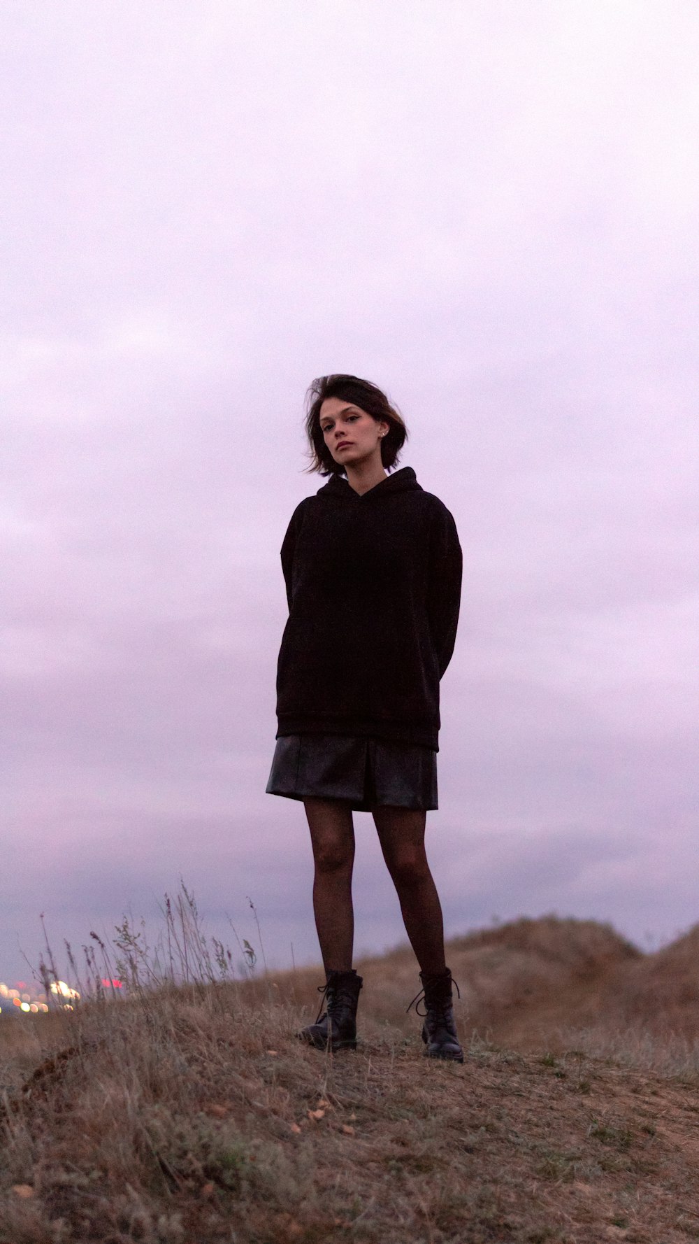 a woman standing on top of a grass covered hillside