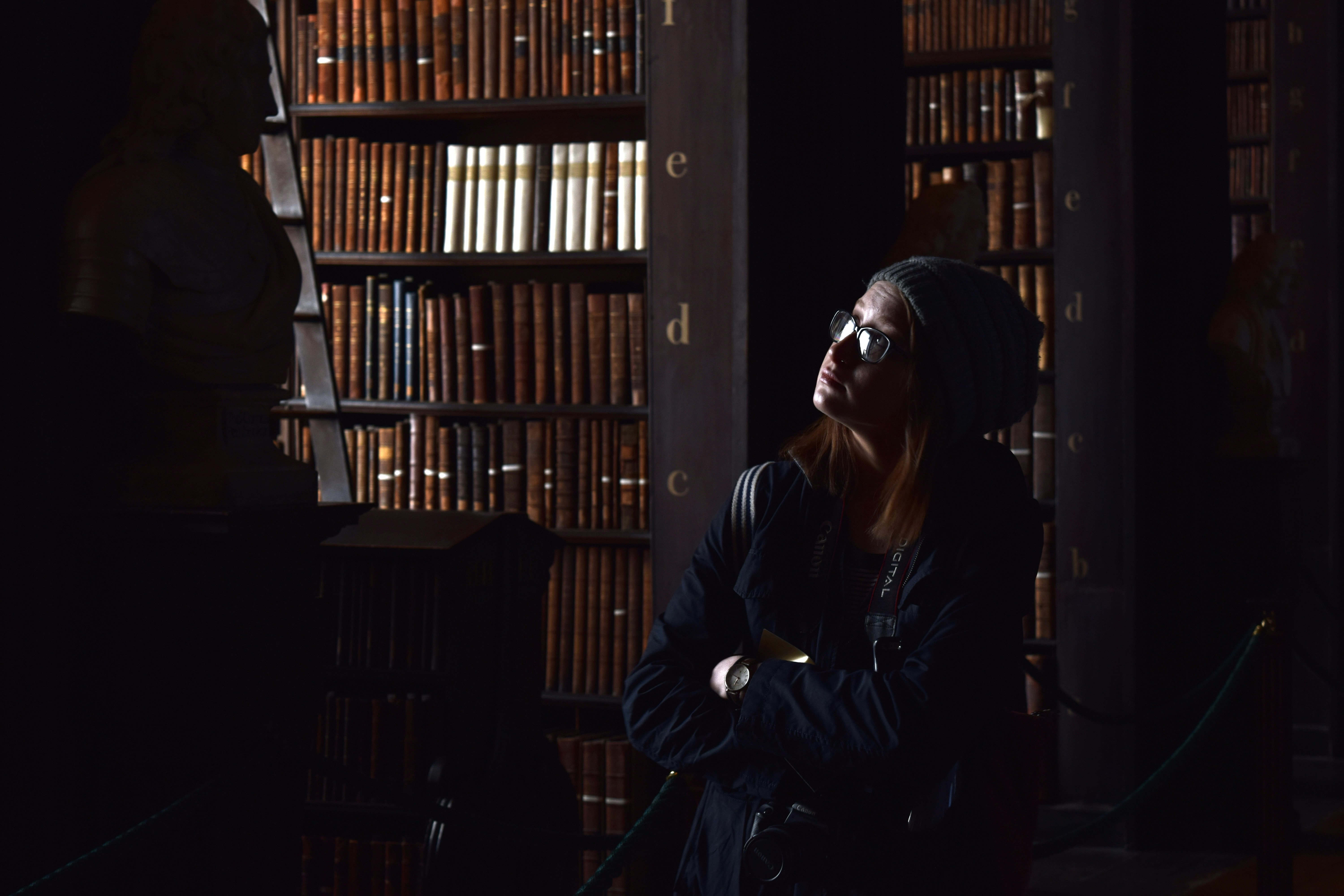 a woman standing in front of a bookshelf, 
