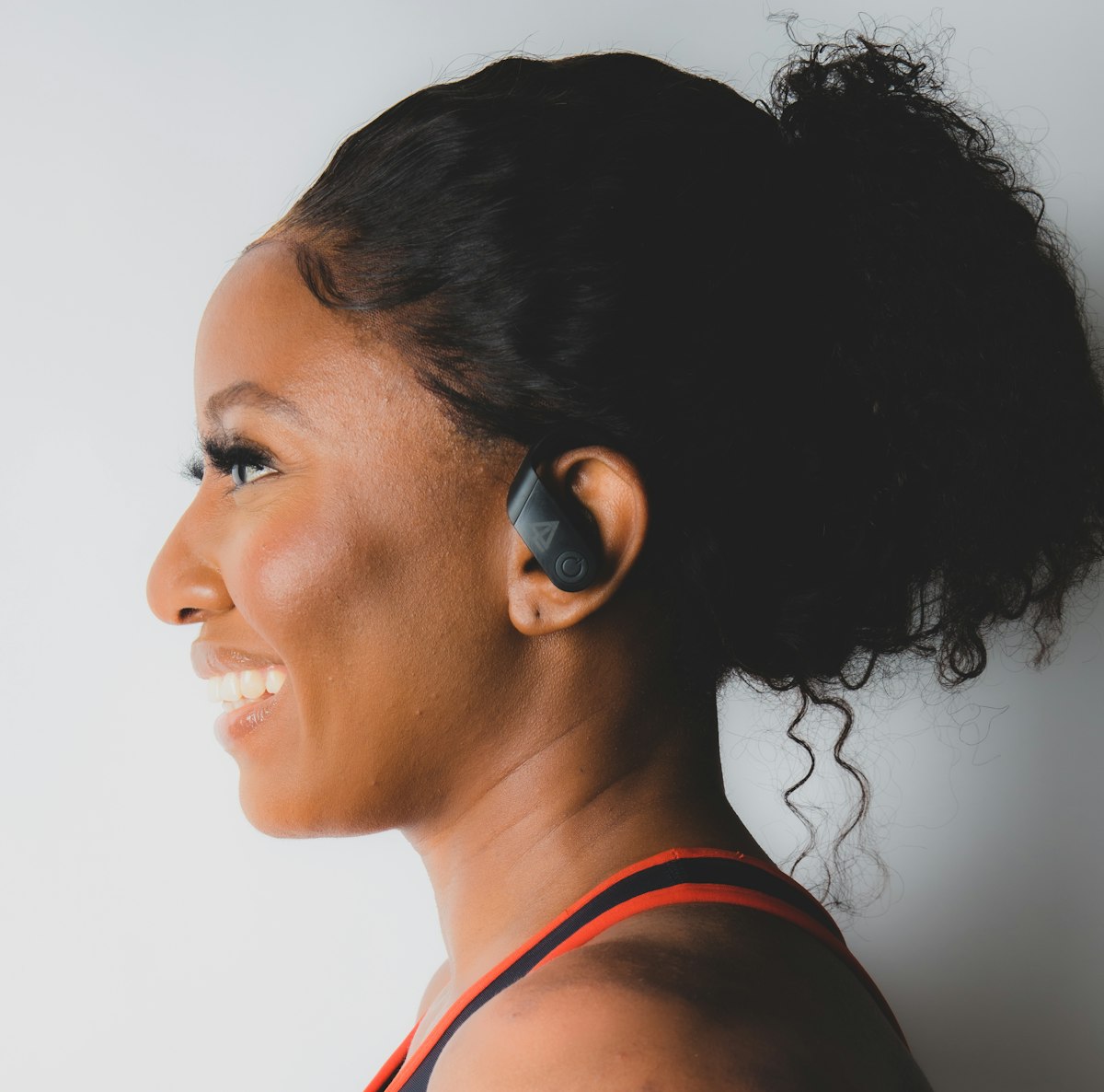 A woman in profile wearing a wireless earbud
