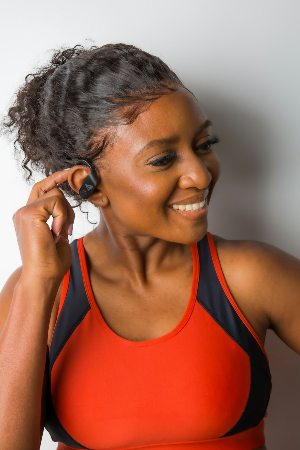 a woman in a sports bra smiling and holding a cell phone to her ear