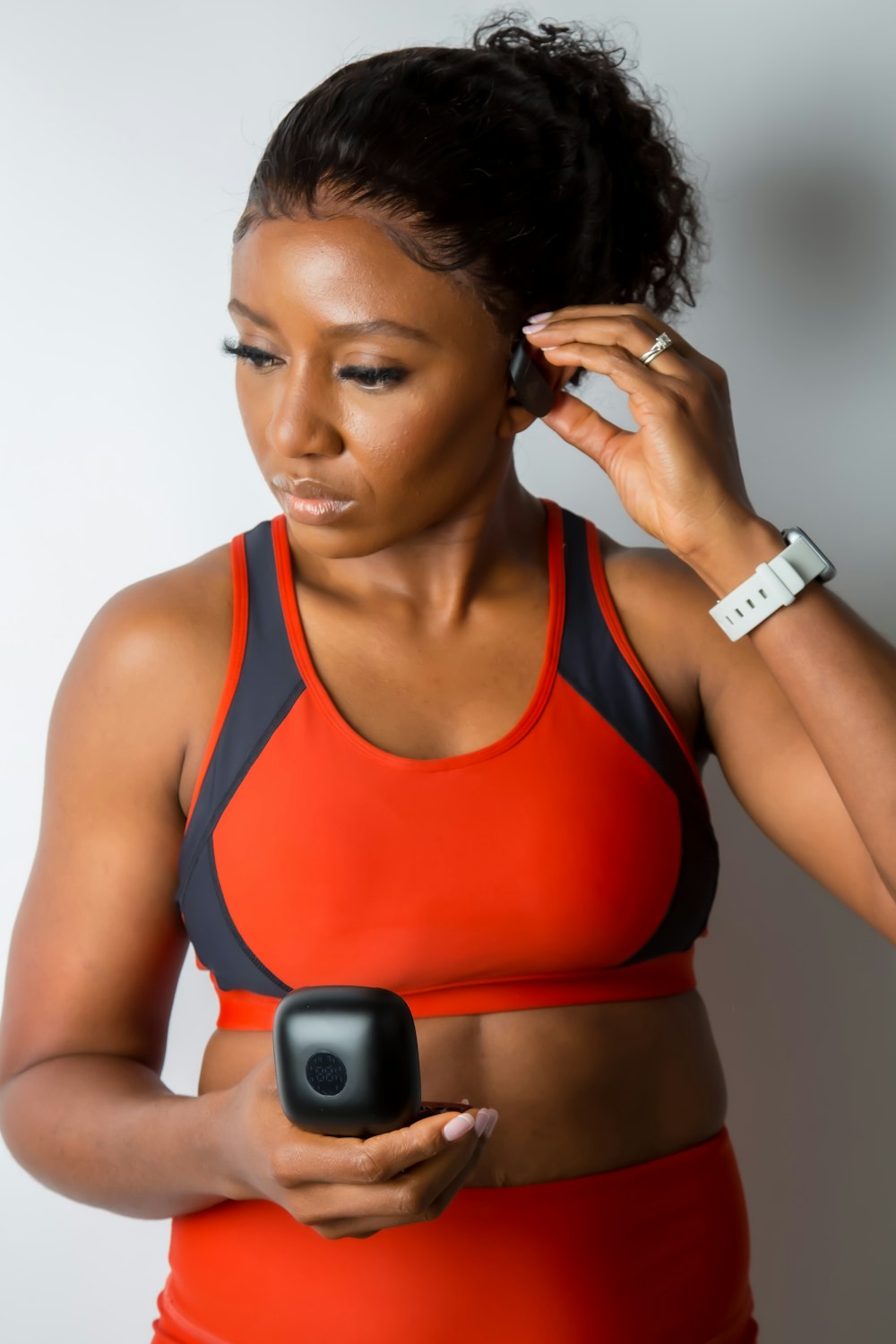 a woman in an orange sports bra holding a cell phone
