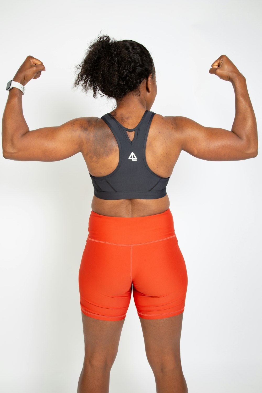 a woman flexing her muscles in front of a white background