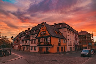 a sunset view of a building with a car parked in front of it