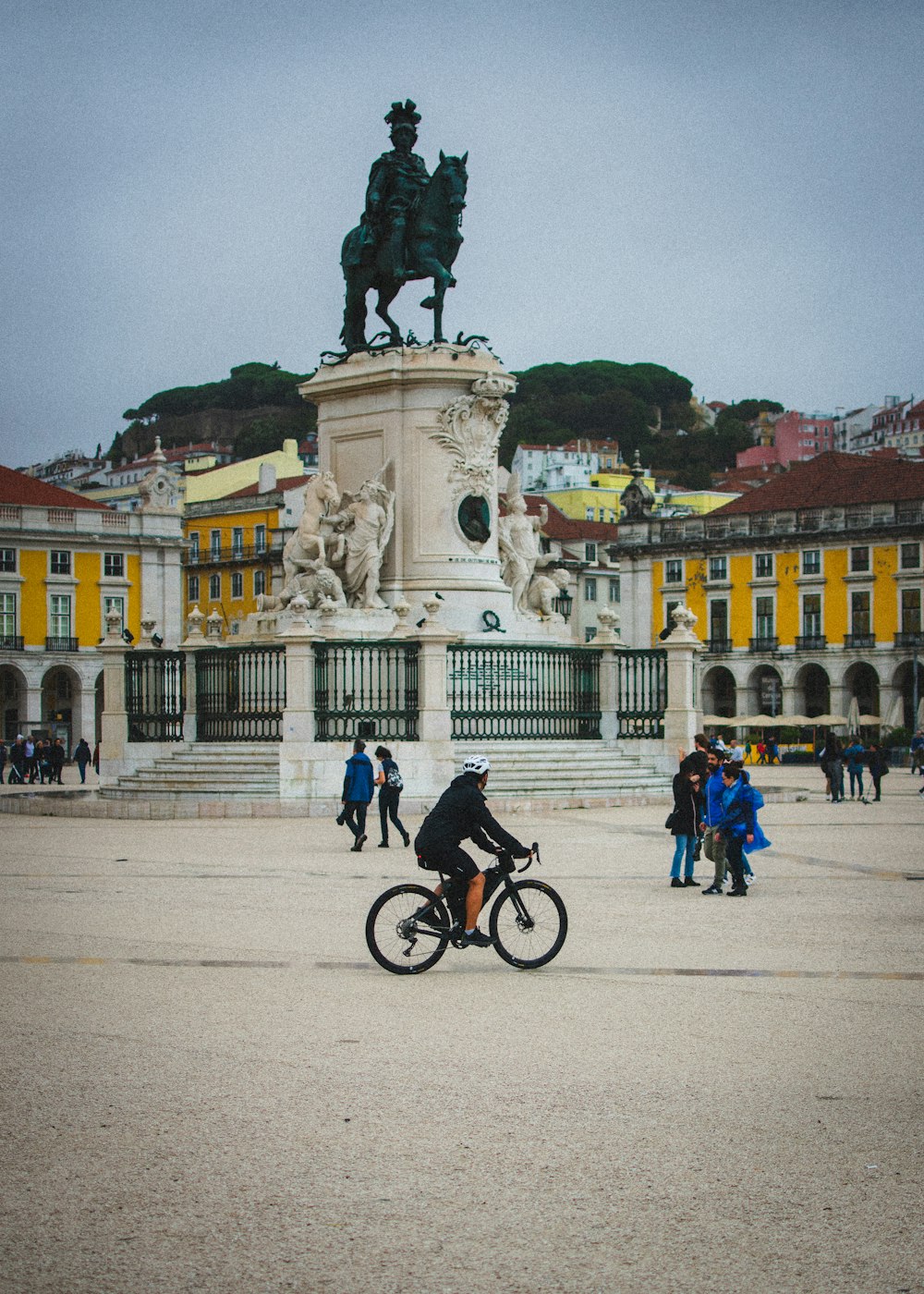 a person riding a bike in front of a statue