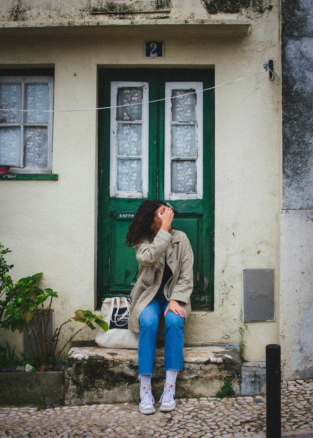 a woman sitting on a step in front of a green door