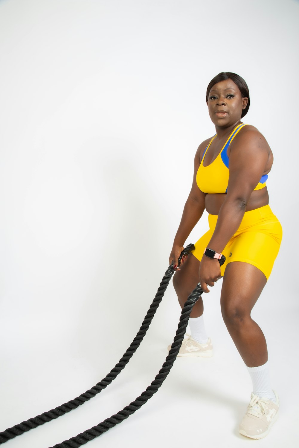 a woman in yellow is holding a black rope