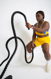a woman in yellow shorts holding a black rope