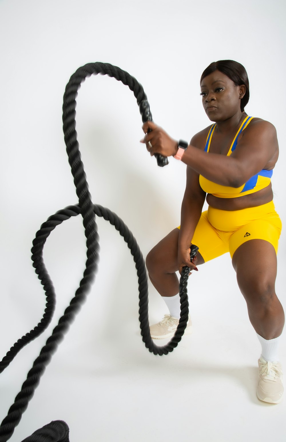 a woman in yellow shorts holding a black rope
