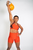 a woman in an orange sports bra holding a kettle