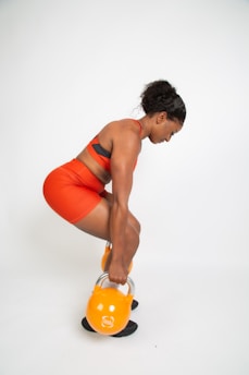 a woman in an orange top is holding a kettle