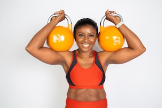 a woman holding two orange kettles over her head