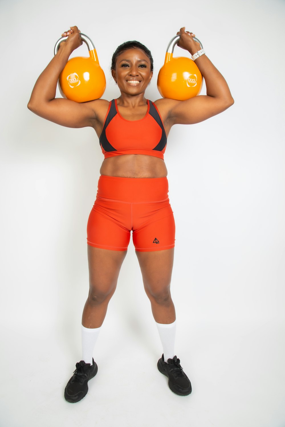 a woman holding two orange kettles over her head