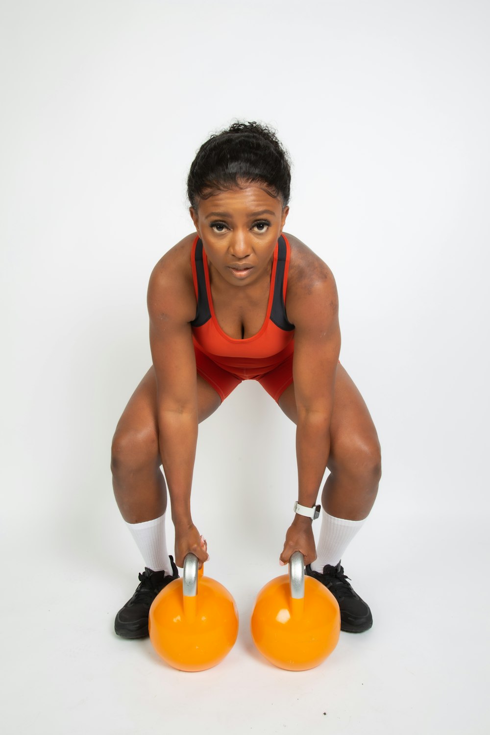 a woman squatting down with two orange balls in front of her