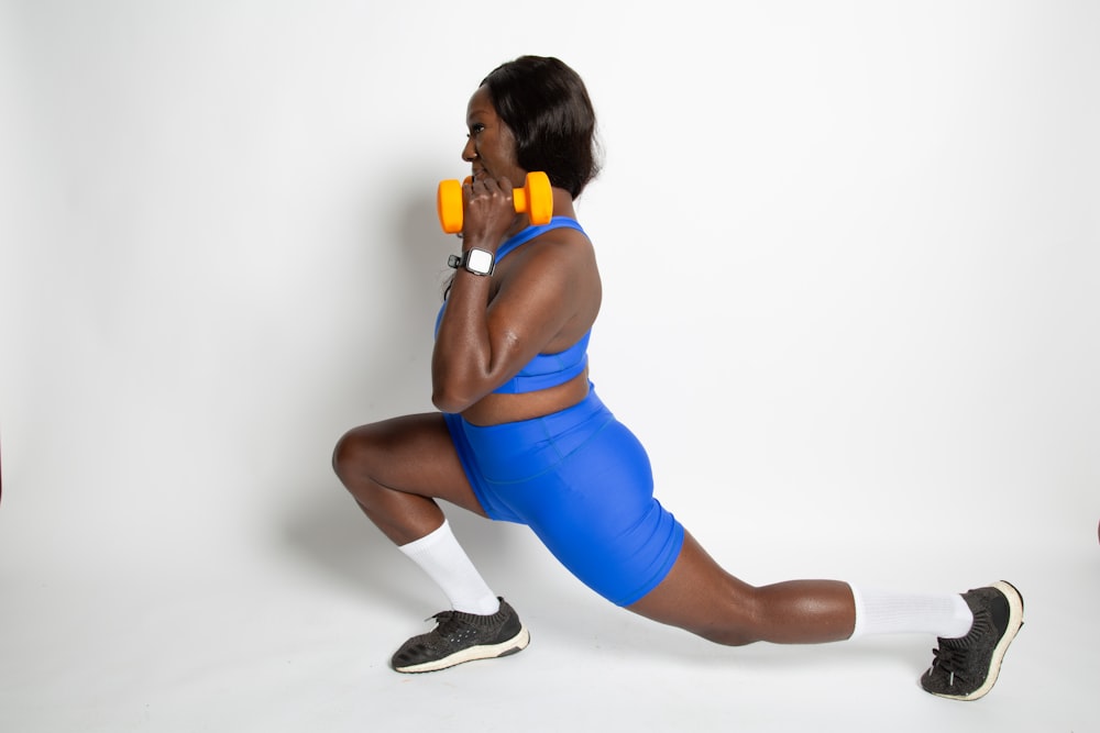 a woman in a blue sports suit holding a pair of yellow dumbbells