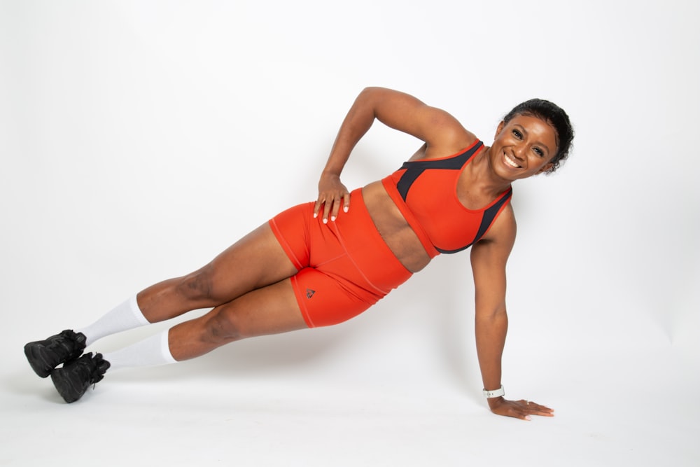 a woman in an orange sports outfit is doing a plank