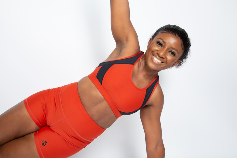 a woman in a red sports bra top and orange shorts