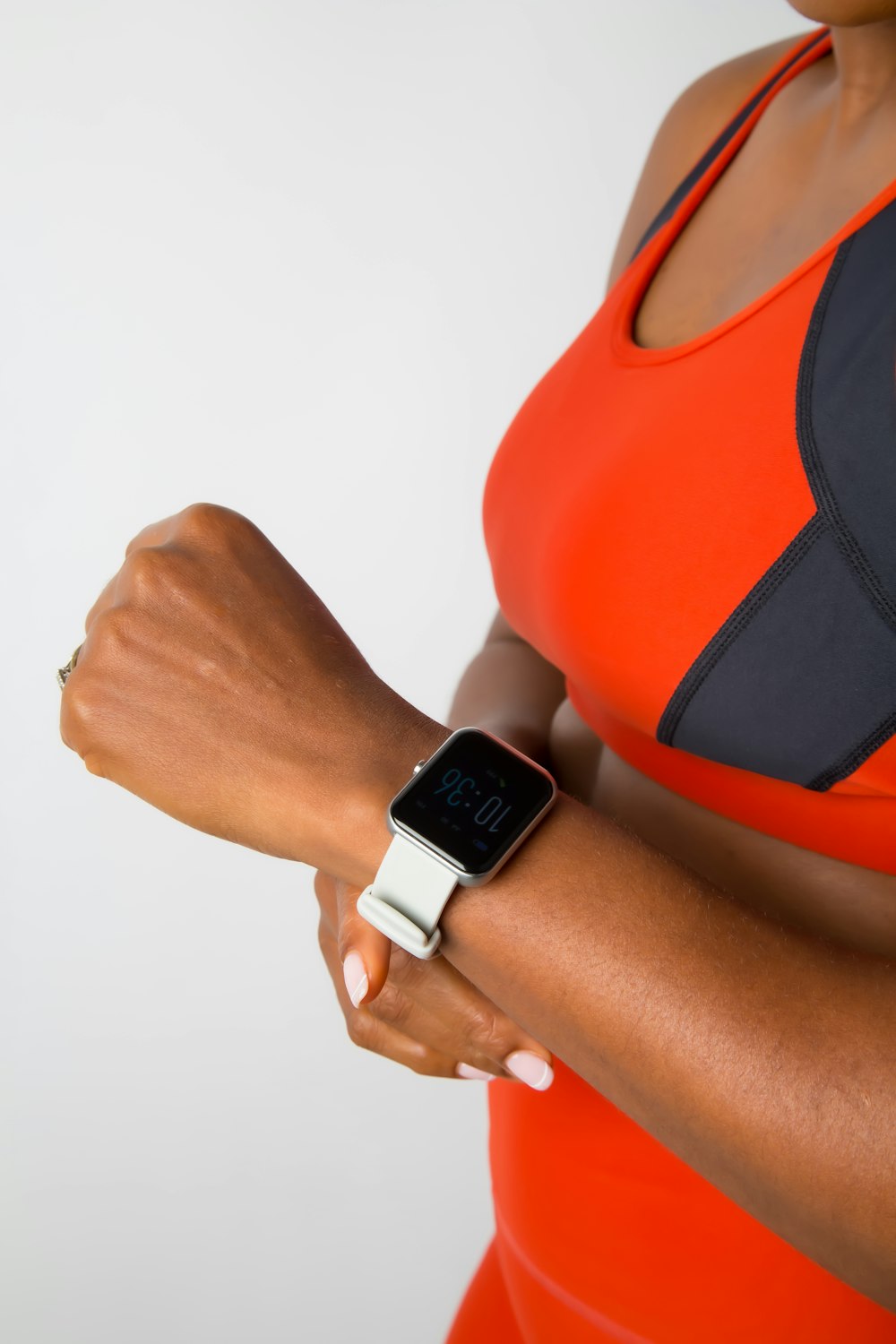a woman in an orange top is holding a smart watch
