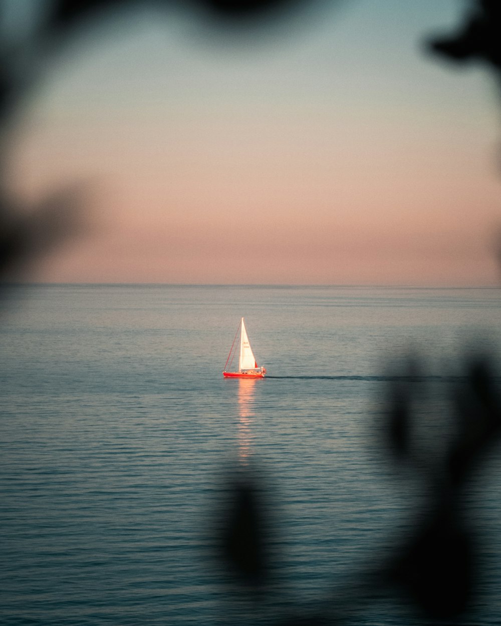 a lone sailboat in the middle of the ocean