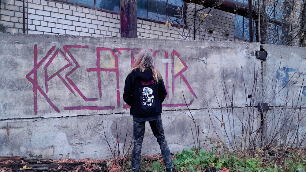 a person standing in front of a wall with graffiti on it