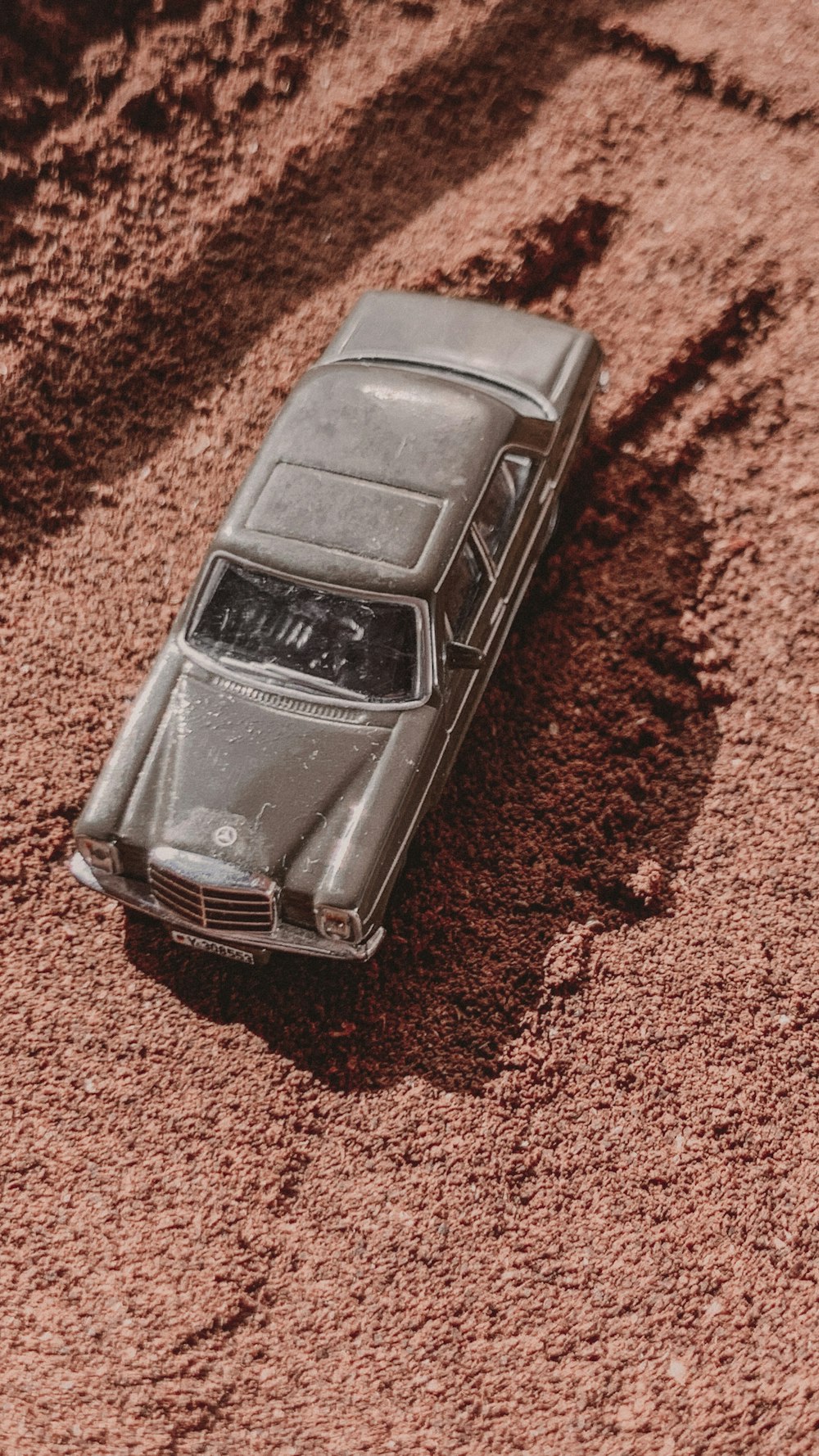 a toy car sitting in the middle of a dirt field