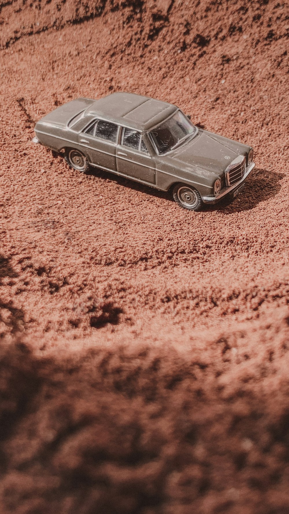 a toy car sitting in the middle of a dirt field