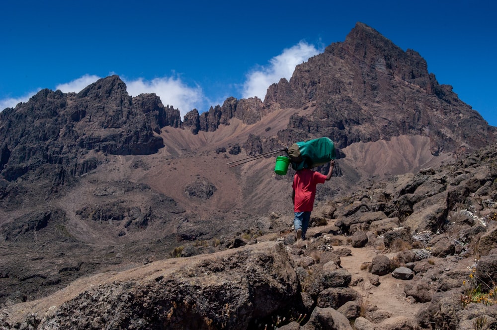 a person with a green backpack walking up a mountain