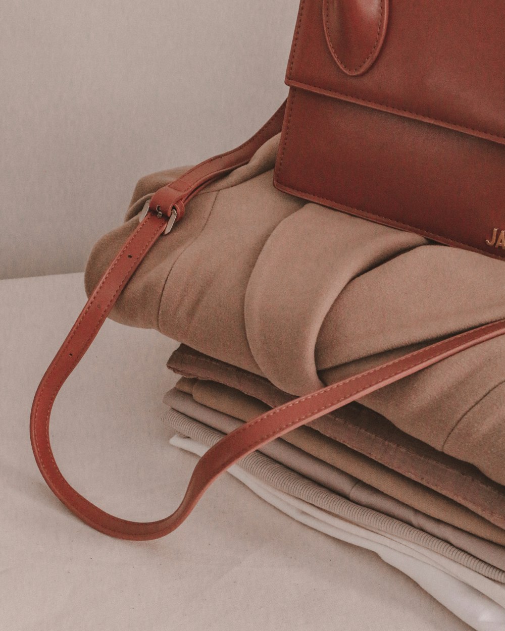 a brown purse sitting on top of a stack of folded papers