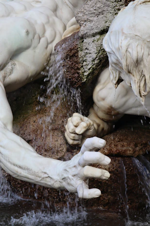Close-up of hands carefully shaping a small decorative waterfall with natural textures.
