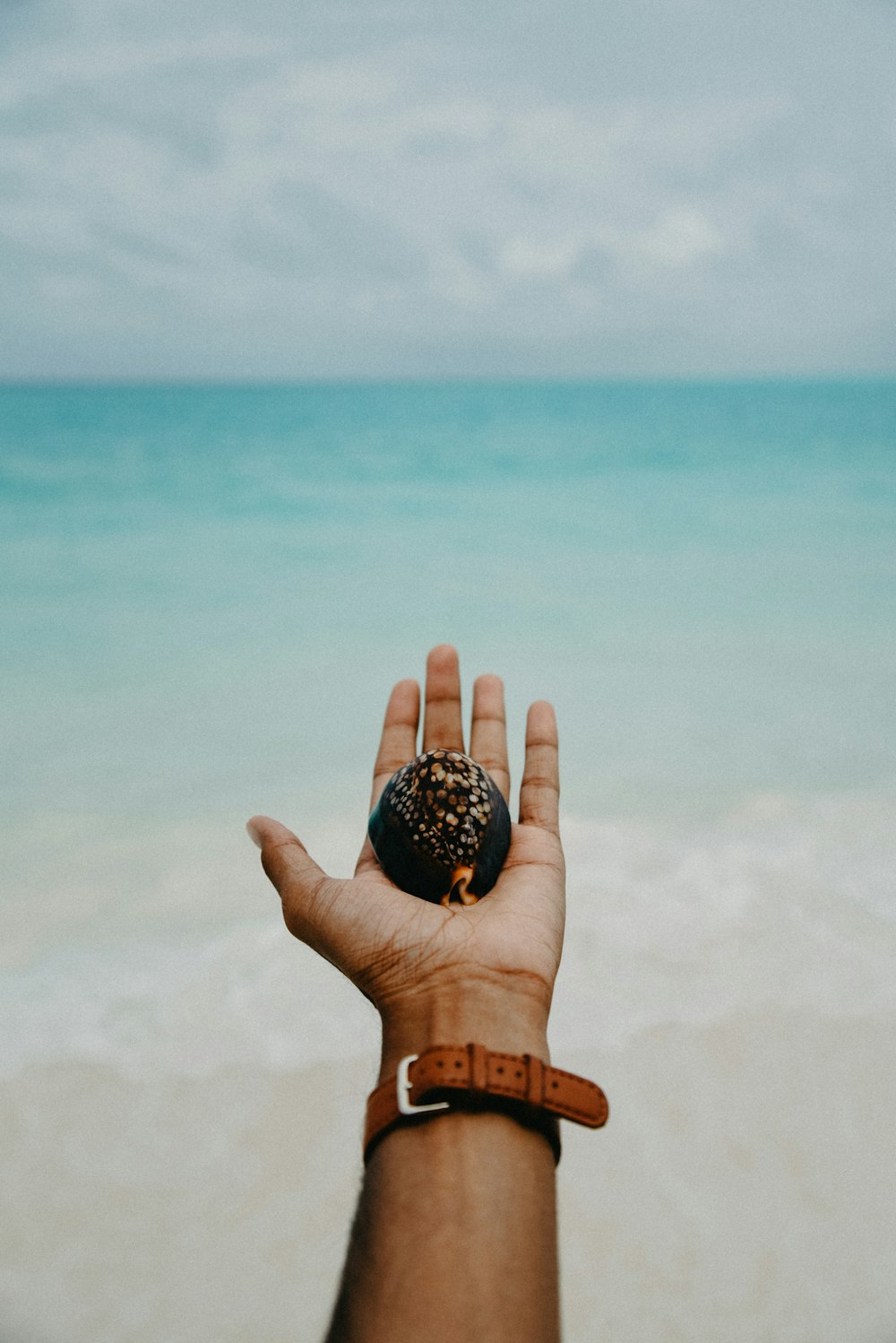 una mano che tiene una ciambella sulla spiaggia