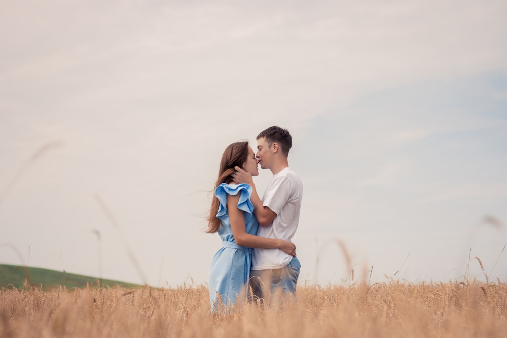 a man and woman standing in a field of tall grass