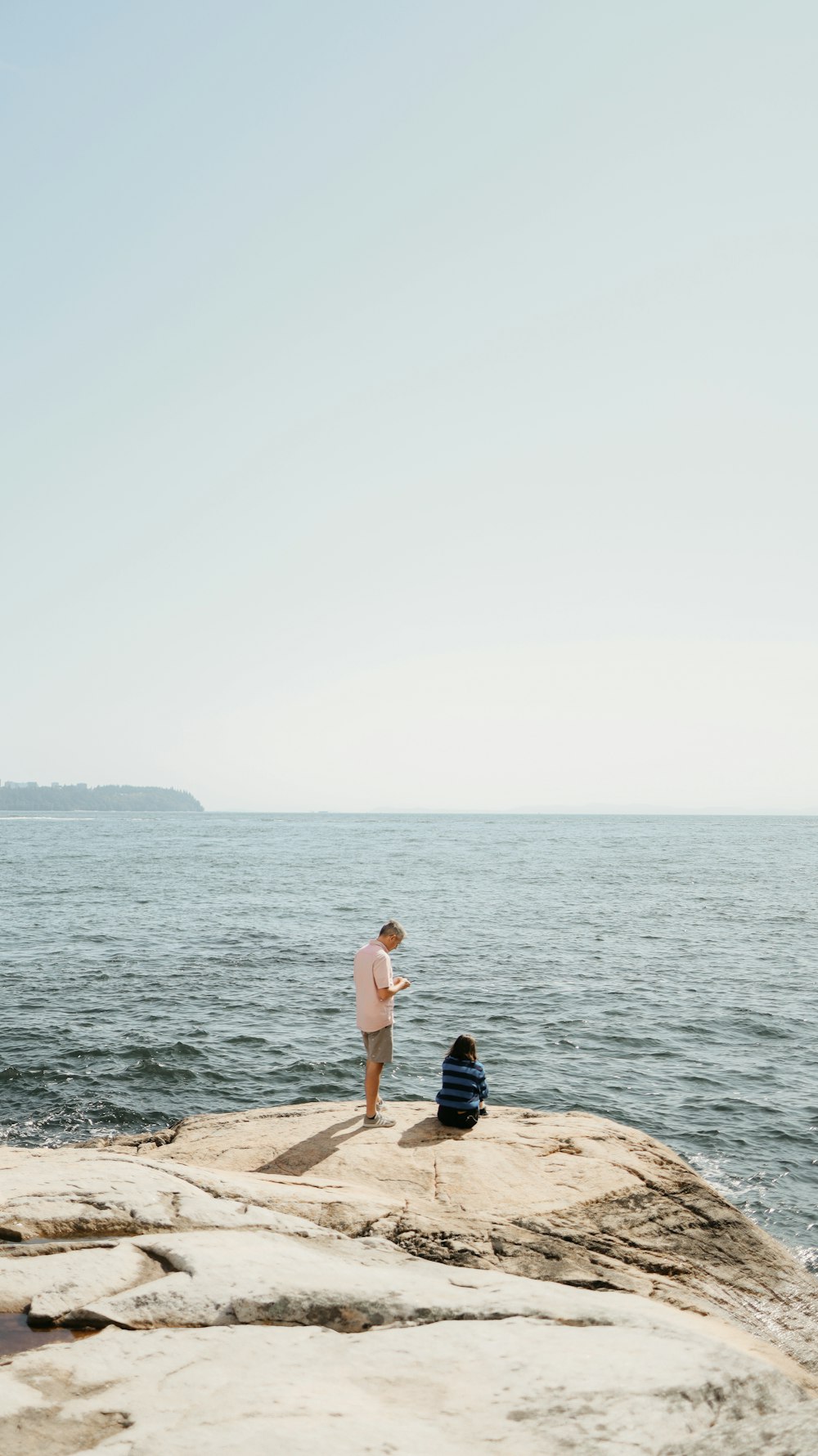 a man standing on top of a rock next to the ocean